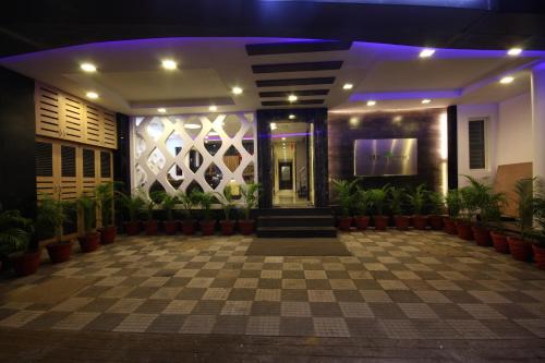 un vestíbulo de un hotel por la noche con plantas en City Home, en Chennai