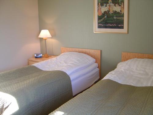 a hotel room with two beds and a lamp on a table at Nordiska Folkhögskolan Bed and Breakfast in Kungälv