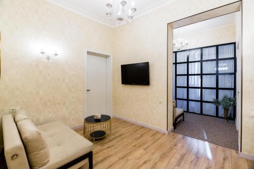 a living room with a couch and a tv on the wall at Dat Exx Apartments On Liberty Square in Tbilisi City