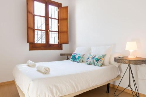 a bedroom with a white bed with a window at Abades Giralda Suite by Valcambre in Seville