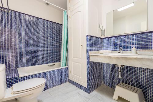 a blue tiled bathroom with a toilet and a sink at Abades Giralda Suite by Valcambre in Seville