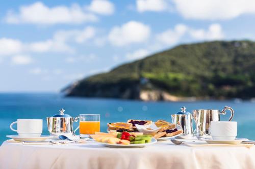 Una mesa con un plato de comida sobre una mesa con el océano. en Hotel Del Golfo, en Procchio