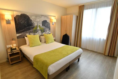 a hotel room with a large bed with yellow pillows at Appart-Hôtel Mer & Golf City Bordeaux Bassins à flot in Bordeaux