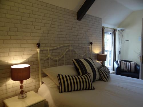 1 dormitorio con cama con almohadas y pared de ladrillo en The Dundry Inn en Winford