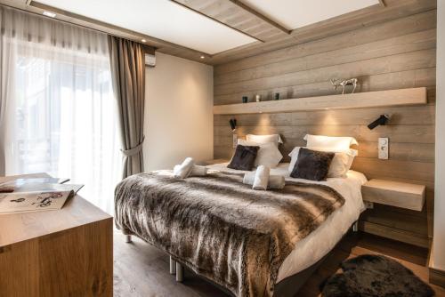 a bedroom with a large bed with a wooden wall at Annapurna by Alpine Resorts in Les Gets