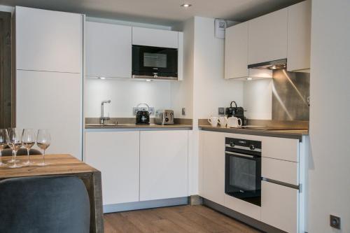 a kitchen with white cabinets and a table with wine glasses at Annapurna by Alpine Resorts in Les Gets