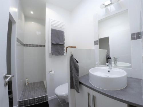 a white bathroom with a sink and a toilet at Le T2 moderne des Palmiers au coeur de Moissac in Moissac