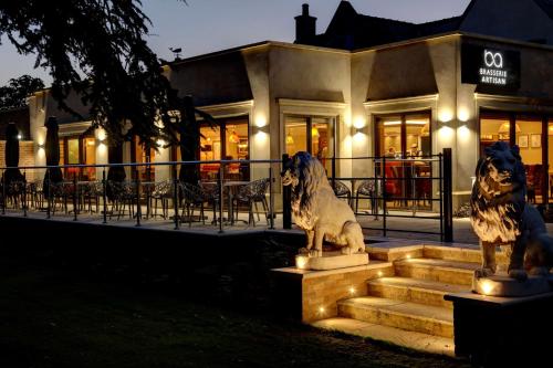 due statue di cani seduti sui gradini di fronte a un edificio di Best Western Premier Doncaster Mount Pleasant Hotel a Doncaster