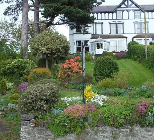 un jardín frente a una casa con flores en Glan Heulog, en Conwy