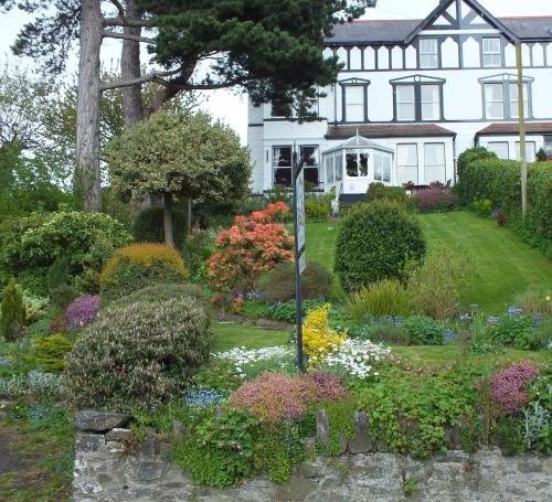 a garden in front of a house with flowers at Glan Heulog Guest House in Conwy