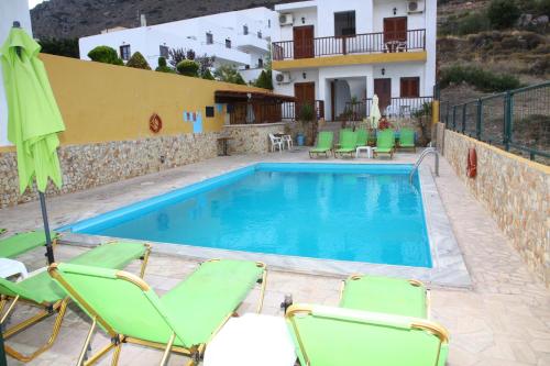 a villa with a swimming pool and chairs and a house at Elgoni Apartments in Hersonissos