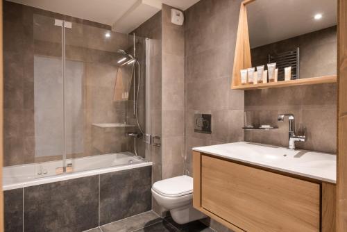 a bathroom with a toilet and a tub and a sink at Annapurna by Alpine Resorts in Les Gets