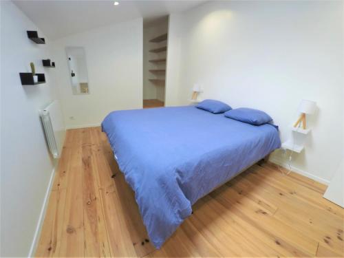 a bedroom with a bed with blue sheets and a wooden floor at Le T2 moderne des Palmiers au coeur de Moissac in Moissac