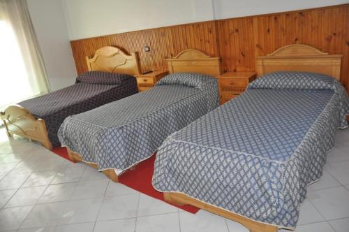 three beds with blue comforters in a room at Hôtel Marina in Tetouan