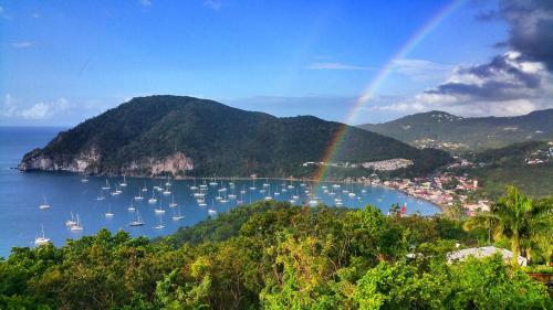 a rainbow over a harbor with boats in the water at Duplex 4 personnes Chambre vue mer Résidence O Coeur de Deshaies in Deshaies