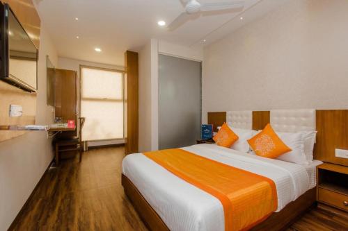 a bedroom with a large bed with orange and white pillows at Hotel Airside in Mumbai
