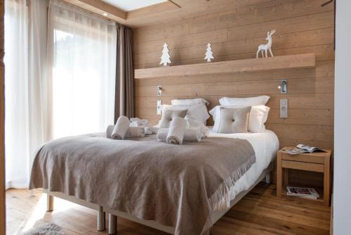 a bedroom with a large bed with a wooden wall at Annapurna by Alpine Resorts in Les Gets