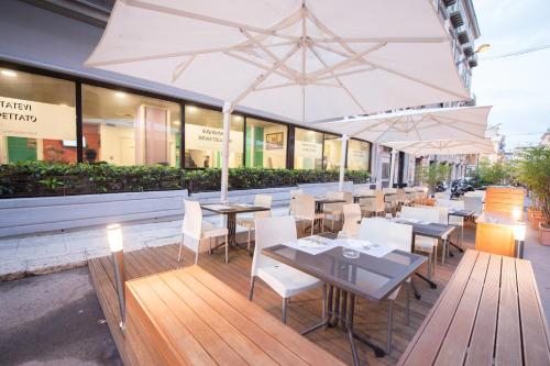 a restaurant with tables and white chairs and umbrellas at Ibis Styles Palermo Cristal in Palermo