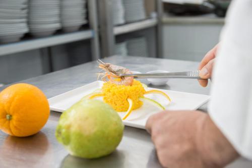 a person cutting up a shrimp on a plate with fruit at Ibis Styles Palermo Cristal in Palermo