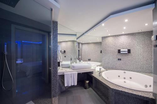 a bathroom with two sinks and a tub and a mirror at Ibis Styles Palermo Cristal in Palermo