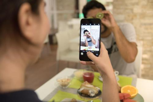 a woman taking a picture with her cell phone of a person eating food at Ibis Styles Palermo Cristal in Palermo