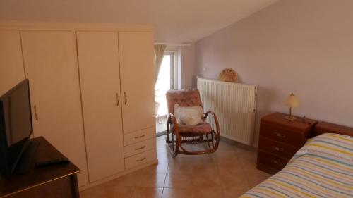 a bedroom with a bed and a chair and a dresser at Villa with the view of Palamidi and Bourtzi in Nafplio