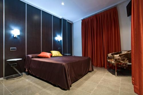 1 dormitorio con cama y cortina roja en Hostal Alcalá Del Jucar, en Alcalá del Júcar