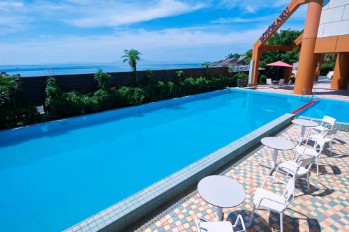 a swimming pool with tables and chairs next to the ocean at Boyokaku in Amakusa