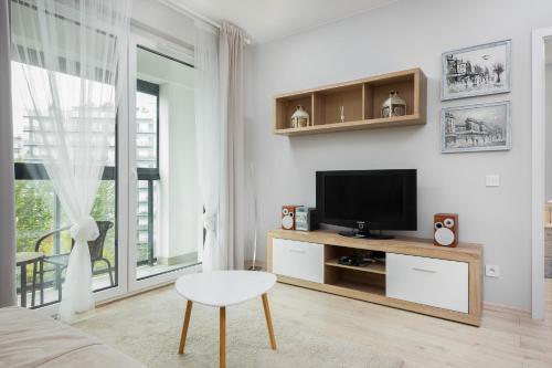 a living room with a television and a table and a chair at Apartments Warsaw Obozowa by Renters in Warsaw