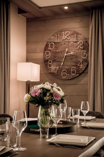 a table with a vase of flowers and a clock at Annapurna by Alpine Resorts in Les Gets