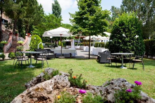 a woman standing in a yard with tables and chairs at Hotel Ristorante Il Pino in Chiusi