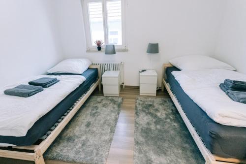 2 Einzelbetten in einem Zimmer mit 2 Tischen in der Unterkunft City Apartment Singen in Singen