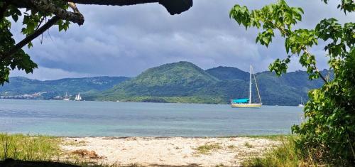 a boat in a body of water with mountains at Bateau Kyma in Sainte-Anne