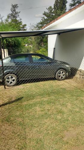 Un coche aparcado en un patio junto a un garaje. en El Tatu, en Villa La Bolsa