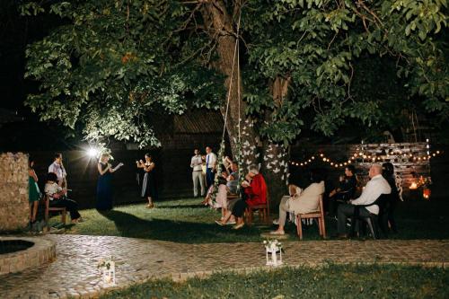 a group of people sitting in chairs under a tree at Casa Pisica Noastra in Breaza