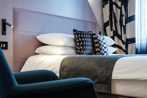 a bedroom with a bed with pillows and a chair at The Fox & Goose Hotel in London