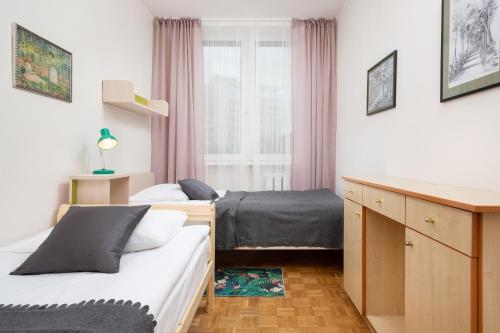 - une chambre avec 2 lits, un bureau et une fenêtre dans l'établissement Apartments Warsaw Arabska, à Varsovie