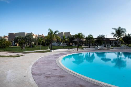 a large swimming pool in a park with buildings in the background at Le Residenze Archimede in Siracusa