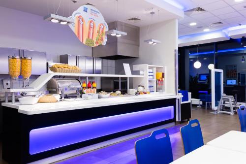 a fast food restaurant with a counter with blue chairs at ibis budget Warszawa West Station in Warsaw