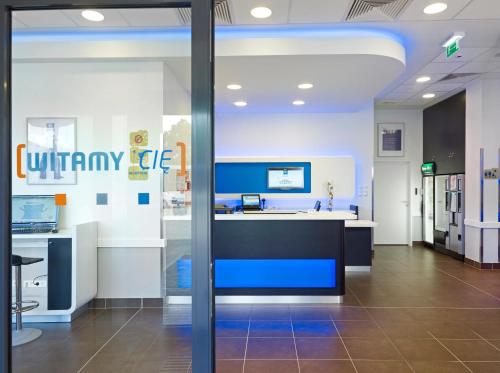 a lobby of an office with a blue and white counter at ibis budget Warszawa West Station in Warsaw