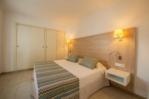 1 dormitorio con 1 cama con cabecero de madera en Apartamentos La Santa Maria, en Cala Millor