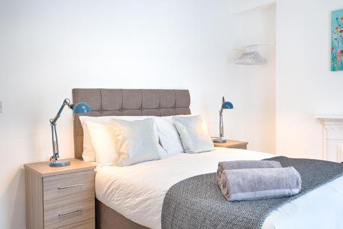 a bedroom with a large bed with white sheets and pillows at Spacious 4BR Home with Garden, Swansea in Swansea