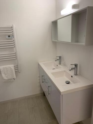 Baño blanco con lavabo y espejo en Aix Hotel, en Aix-en-Provence
