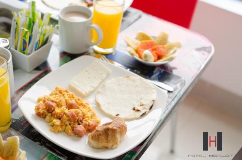a table with a plate of breakfast food and drinks at Hotel Merlott 70 in Medellín