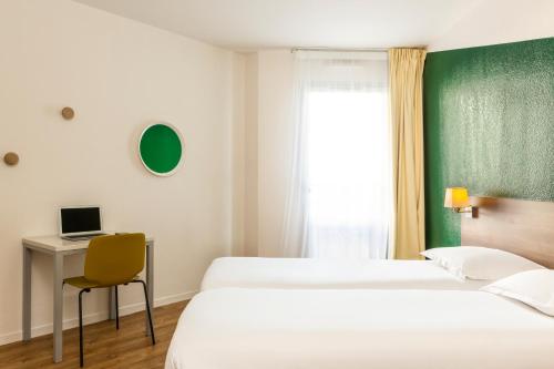 a bedroom with two beds and a desk with a computer at Aparthotel Adagio Access Carrières Sous Poissy in Carrières-sous-Poissy