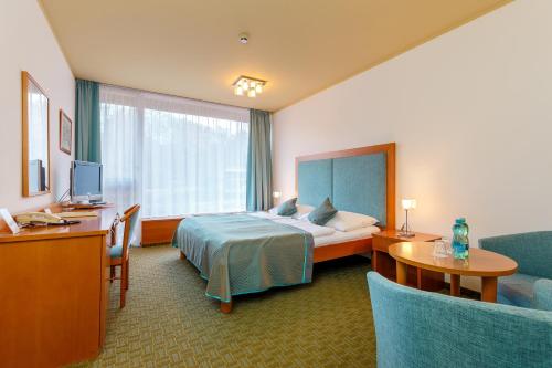 a hotel room with a bed and a desk and a tv at Hotel Thermal in Karlovy Vary