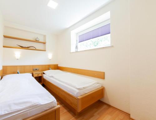 two beds in a small room with a window at Appartementhaus EifelAdventures in Berlingen