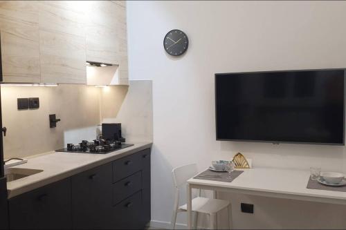 eine Küche mit einem TV an der Wand und einem Tisch in der Unterkunft JOIVY Heart of the City 1 Bed Apt near Castle Belvedere in Genua
