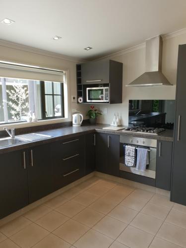 a kitchen with black cabinets and a sink at Accommodation at Lakeside in Oamaru