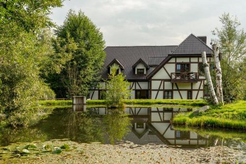 a house with a pond in front of it at Osada Górski Potok in Szczawina